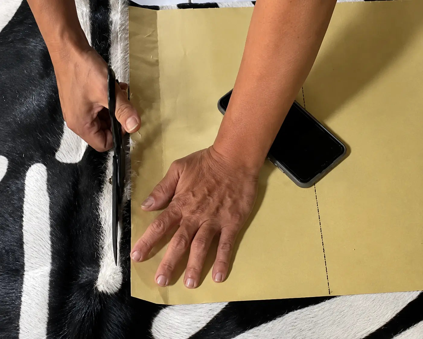 person cutting leather into bag shape